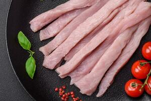 Raw chicken or turkey fillet cut into strips with spices and herbs photo