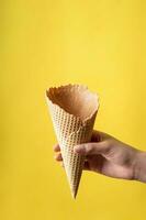 Young woman holding sweet wafer cone - yellow background photo