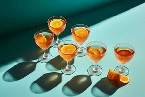 four glasses filled with different types of Spritz cocktail drinks on top of a aquamarine table photo