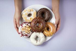 female hands holding delicious donuts on a plate - top view purple background photo