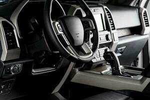New car interior with luxury details, automatic transmission and steering wheel with electric buttons - dark lighting photo