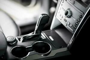 Car inside, automatic transmission close up, cup holders and armrest, black leather seats photo