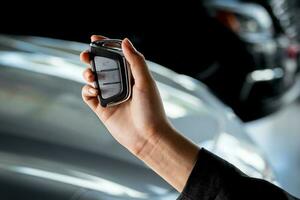 Hand of a young Korean business woman holding the key of a new car inside a car dealership - car saleswoman, professional service photo