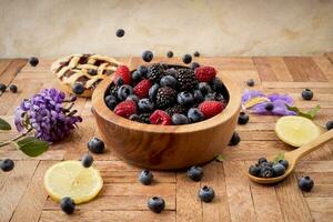 Mix of blueberries, blackberries and raspberries in a wooden bowl - healthy breakfast photo