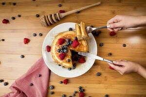 eating blueberry pancakes, bamboo wood background photo