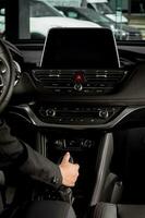 Young woman's hand holding an automatic gear lever driving inside a new car in traffic photo