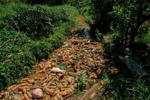 Piles of waste left over from plastic beverage bottles in ditches which cause water to clog and not flow can cause flooding photo