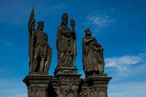 Antique statue of Saints Norbert of Xanten, Wenceslas and Sigismund on the medieval gothic Charles Bridge in Prague built on the 15th century photo