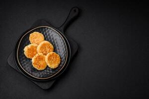 delicioso Fresco cabaña pasteles de queso con Pasas y vainilla en un negro cerámico plato foto