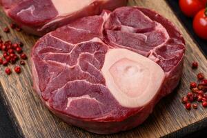 Fresh raw beef steak with bone or ossobuco with salt, spices and herbs photo