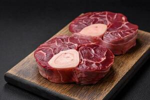 Fresh raw beef steak with bone or ossobuco with salt, spices and herbs photo