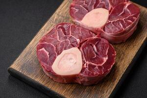 Fresh raw beef steak with bone or ossobuco with salt, spices and herbs photo