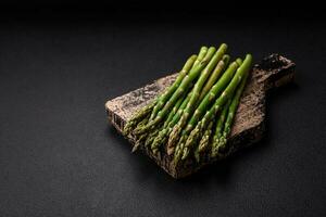 Delicious fresh sprigs of asparagus on a dark textured background photo