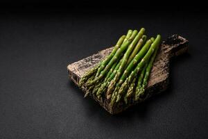 Delicious fresh sprigs of asparagus on a dark textured background photo