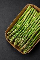 Delicious fresh sprigs of asparagus on a dark textured background photo