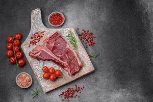 Raw juicy beef t-bone steak with salt, spices and herbs photo