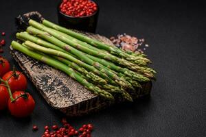 Delicious fresh sprigs of asparagus on a dark textured background photo