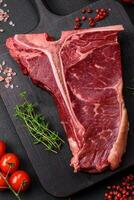 Raw juicy beef t-bone steak with salt, spices and herbs photo