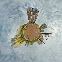 tiny planet in blue sky with clouds in city center near modern skyscrapers in residential complex. Transformation of spherical 360 panorama in abstract aerial view. photo