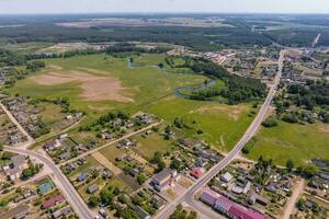 panoramic aerial view of eco village with wooden houses, gravel road, gardens and orchards photo