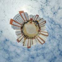 tiny planet in blue sky with clouds in city center near modern skyscrapers in residential complex. Transformation of spherical 360 panorama in abstract aerial view. photo