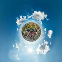 tiny planet in sky with clouds overlooking old town, urban development, historic buildings and crossroads. Transformation of spherical 360 panorama in abstract aerial view. photo