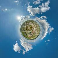 tiny planet in sky with clouds overlooking old town, urban development, historic buildings and crossroads. Transformation of spherical 360 panorama in abstract aerial view. photo