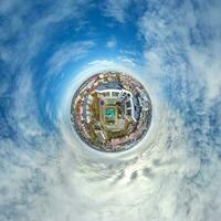 pequeño planeta en el cielo con nubes que dominan el casco antiguo, el desarrollo urbano, los edificios históricos y los cruces. transformación del panorama esférico 360 en vista aérea abstracta. foto