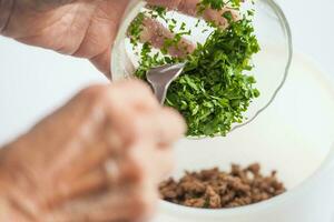 Step by step Levantine cuisine kibbeh preparation. Mixing the ingredients to prepare kibbeh filling into a bowl photo