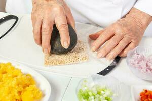 Preparation of the traditional patties from the region of Cauca in Colombia, called empanadas de pipian - Senior woman preparing the filling for the patties photo