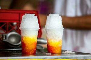 Street vendor in the city of Cali in Colombia preparing and selling a traditional sweet water ice called cholado photo