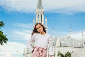 hermosa joven niña a el río bulevar en frente de el famoso gótico Iglesia de la ermita construido en 1602 en el ciudad de cali en Colombia foto