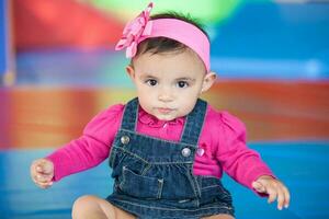 retrato de un hermosa diez meses bebé niña en un vistoso antecedentes. temprano estímulo para niños pequeños concepto. foto