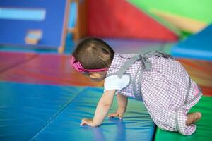 Beautiful ten months baby girl crawling on a colorful background. Early stimulation for toddlers concept. photo