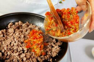 preparación de suelo carne de vaca con el tradicional Colombiana hogao o criollo salsa hecho de preparación de el tradicional Colombiana hogao o criollo salsa hecho de cebolla, tomate, pimientos y cilantro. foto