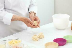 Senior woman preparing dough for a delicious cheese and ham tartlet photo