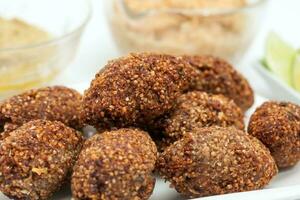 Step by step Levantine cuisine kibbeh preparation. Ready fried kibbeh served with tahini and hummus photo