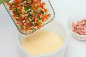 Omelet preparation. Mixing ingredients with scrambled eggs photo