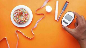 diabetic measurement tools, insulin and donuts on orange background video