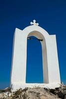 hermosa pequeño campana torre a un Iglesia siguiente a el caminando camino Entre fira y oia en santorini isla foto