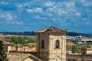 cigüeñas anidamiento en parte superior de el campana torre de Iglesia de carmen Delaware abajo construido en el 15 siglo en el ciudad de salamanca en España foto