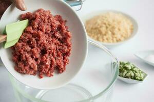 paso por paso levantino cocina kibbeh preparación. agregando el ingredientes a preparar kibbeh dentro un cuenco foto