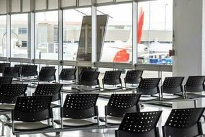 vacío esperando habitación a un aeropuerto durante codicioso 19 pandemia con social distanciamiento señales en sillas foto