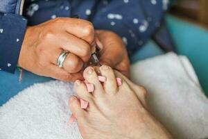 cerca arriba de un mayor mujer pie mientras consiguiendo un pedicure a hogar durante codicioso 19 pandemia foto