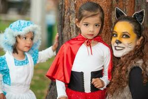 real familia teniendo divertido mientras utilizando disfraces de el pequeño rojo montando capucha cuento en Víspera de Todos los Santos. foto