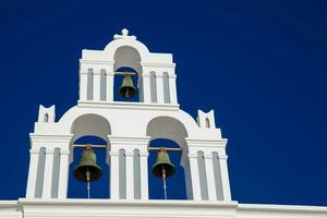 Traditional bell tower of the churches in Santorini Island against a deep blue sky photo