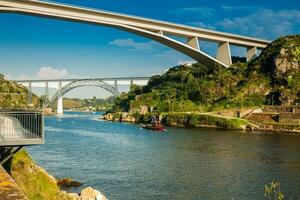 View of a vintage traditional boat sailing on the Douro River and some of the bridges that cross over it photo