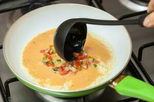 Omelet preparation. Pouring the omelet mix onto a pan photo