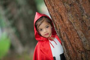 Sweet girl wearing a Little red riding hood costume. Real family having fun while using costumes of the Little red riding hood tale in Halloween. photo