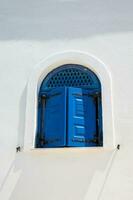 Traditional beautiful blue windows over white walls in Santorini Island photo